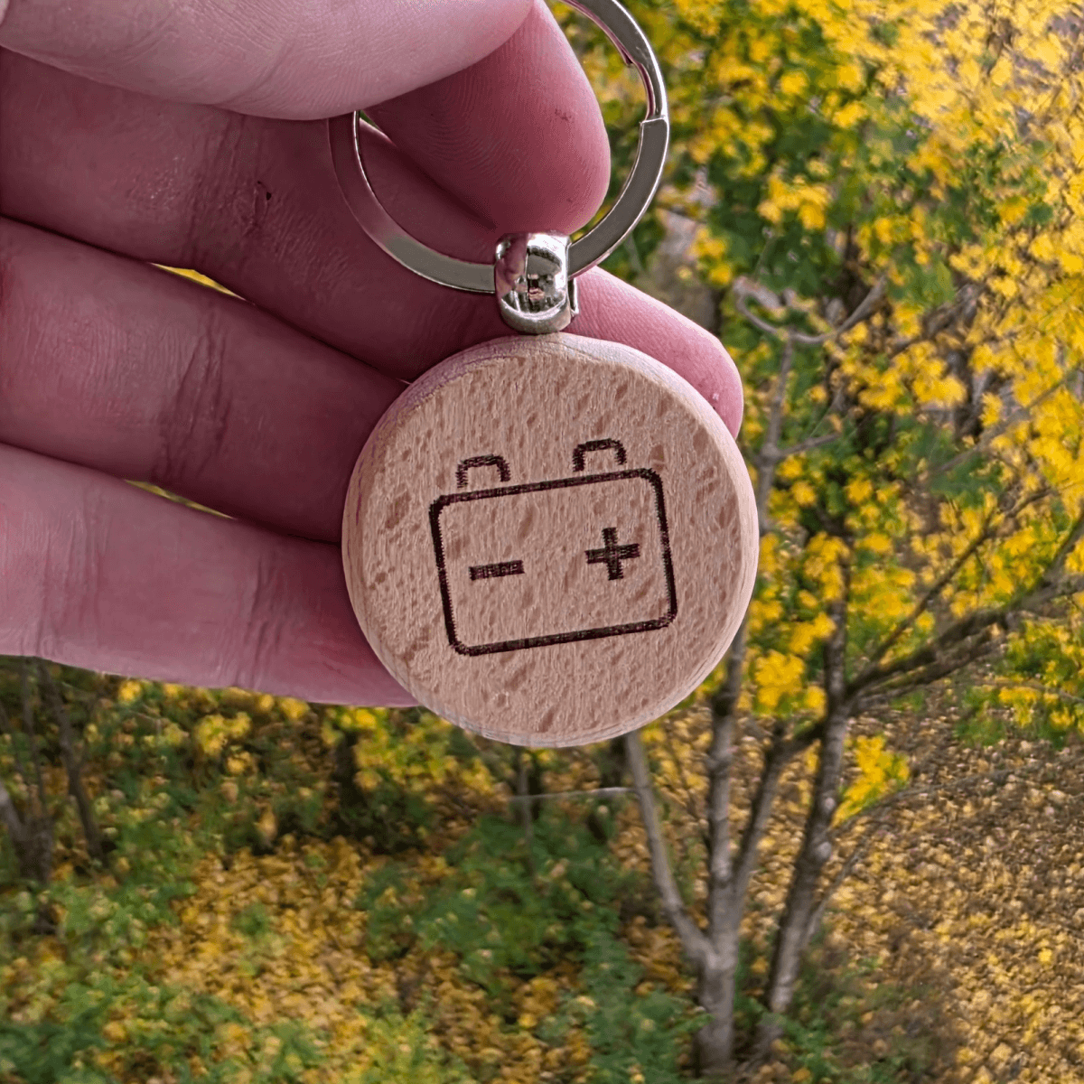 Battery/charging icon engraved on round wooden keychain