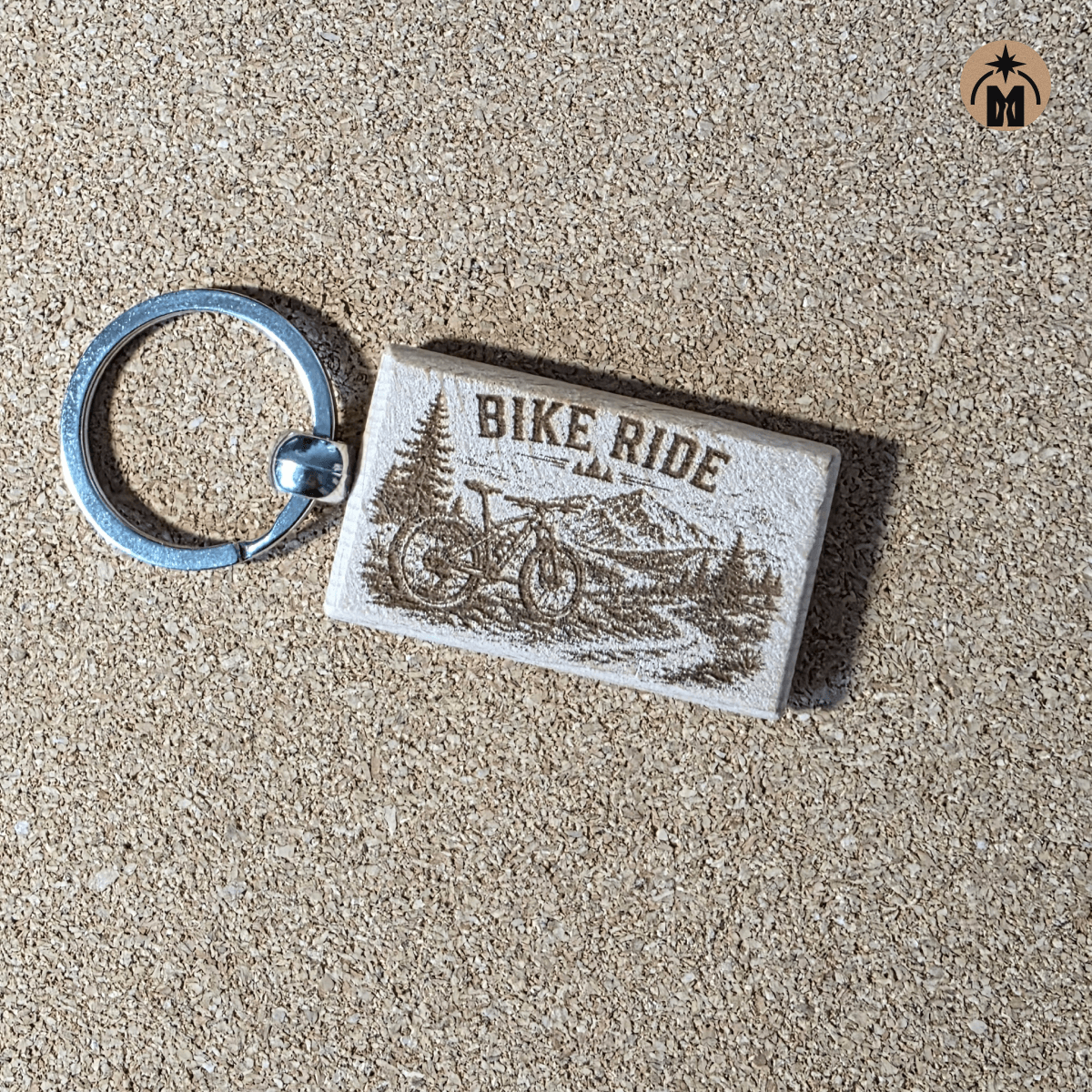 Wooden cycling keychain with bike trail design on natural background