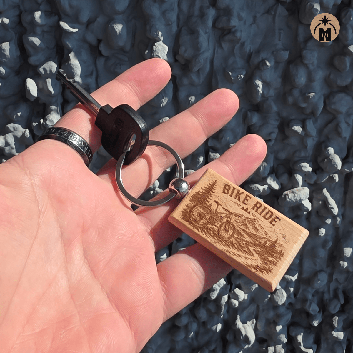 Beech wood bicycle keychain shown in hand with detailed outdoor engraving