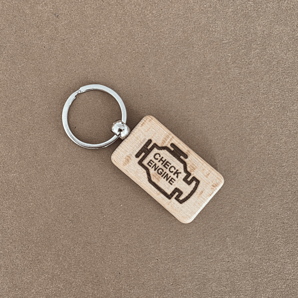 Wooden keychain with laser-engraved CHECK ENGINE icon on beech