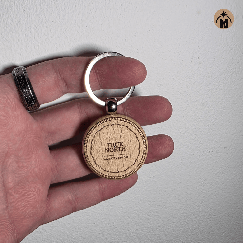 Wooden keychain engraved with TRUE NORTH motto, matte clear finish, steel key ring