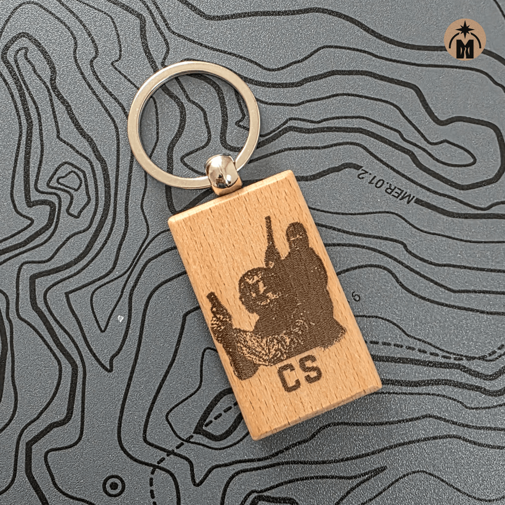 Laser engraved wooden CS gamer keychain with metal key ring on dark background