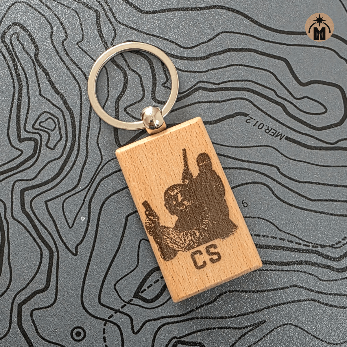 Laser engraved wooden CS gamer keychain with metal key ring on dark background