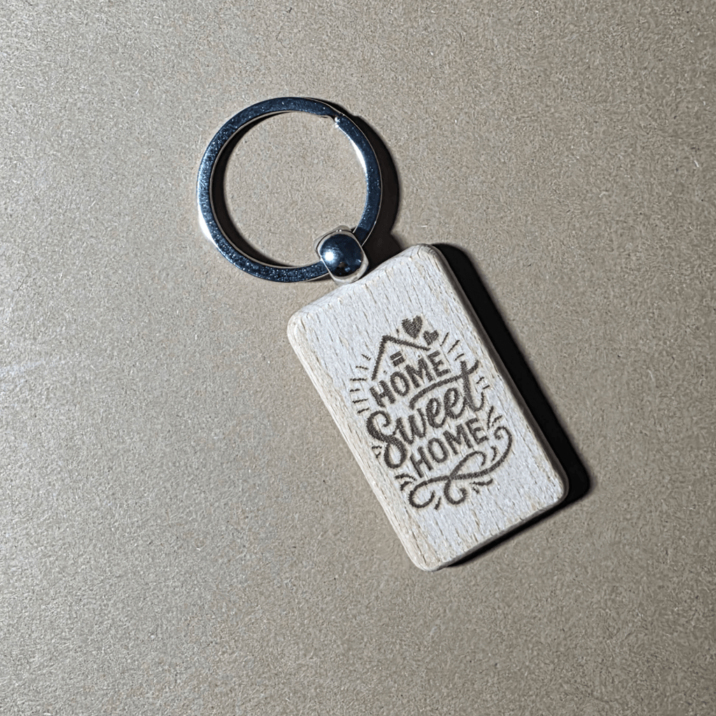 Engraved wooden keychain with “Home Sweet Home” text on beige background