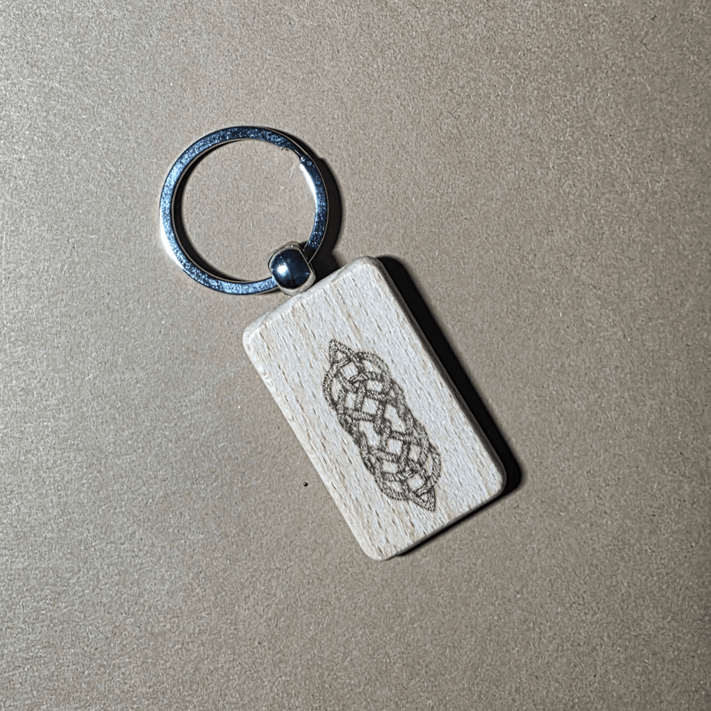 Hand holding a Celtic knot beech wood key fob with metal ring