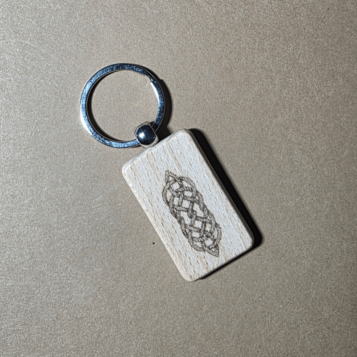 Hand holding a Celtic knot beech wood key fob with metal ring
