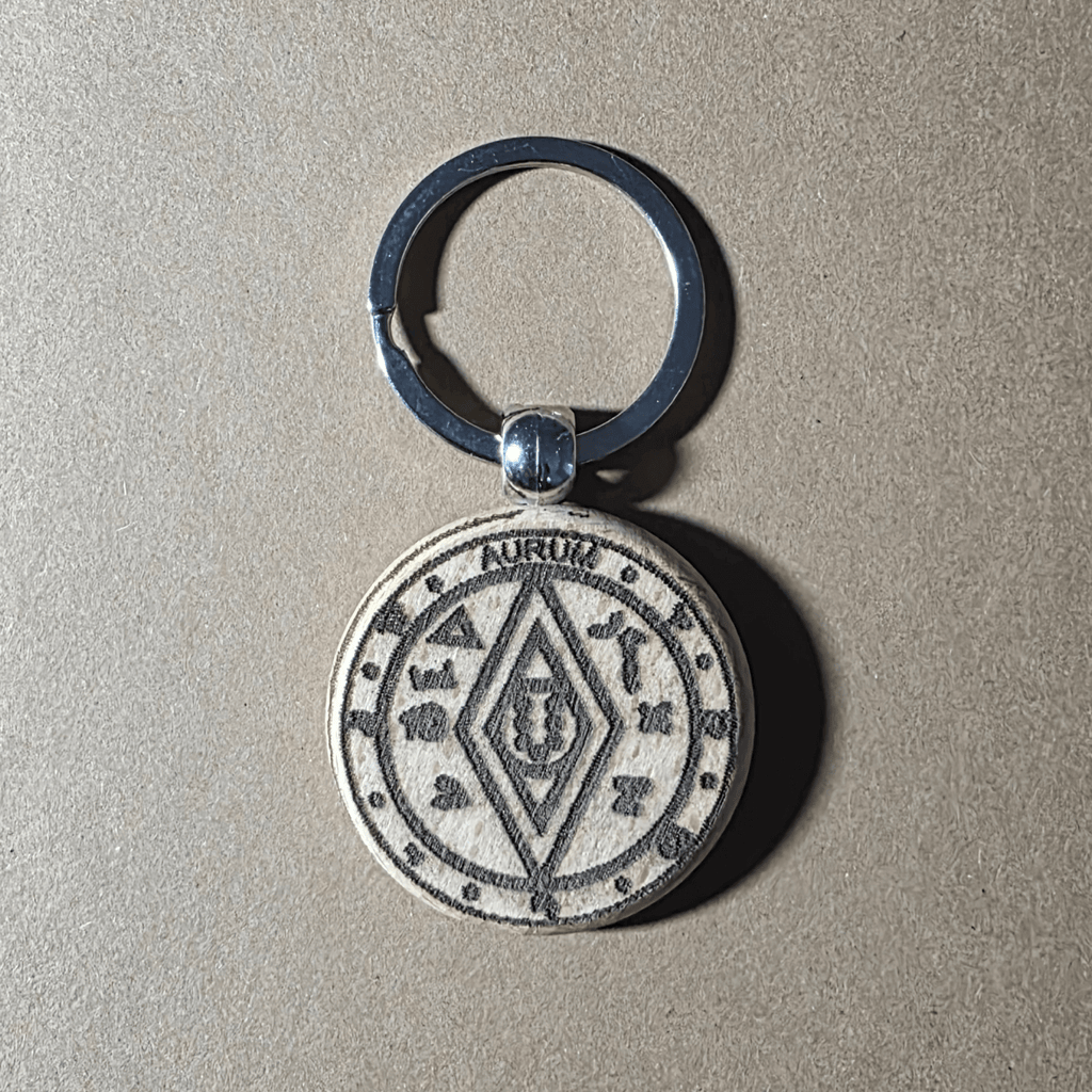 Light-finish wooden keychain with money-luck talisman motif (front)