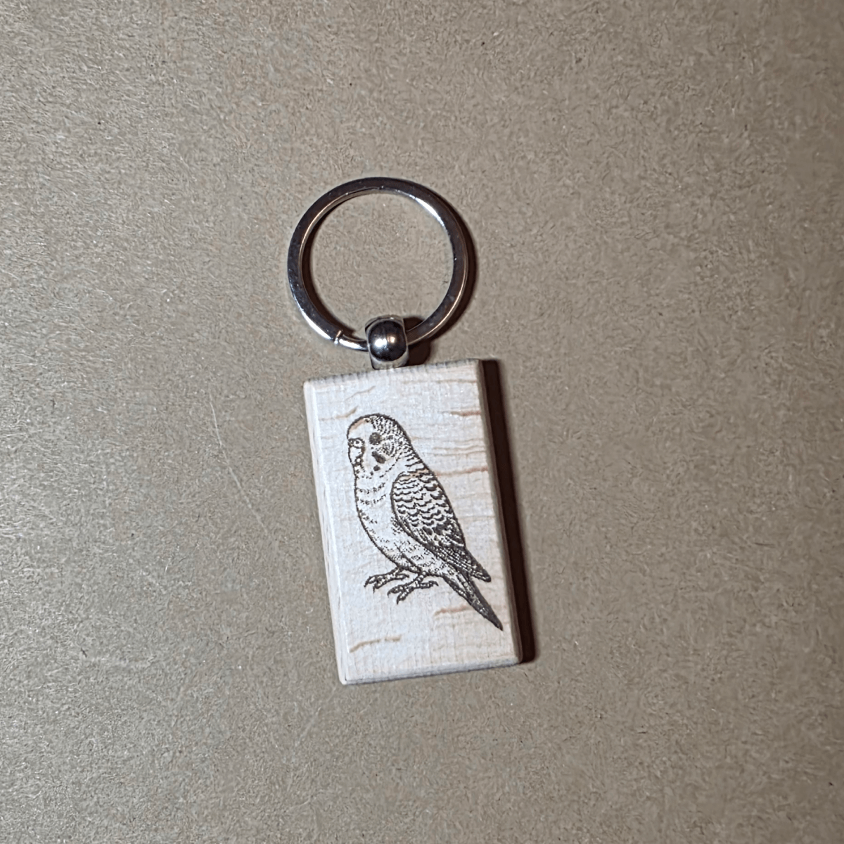 Laser engraved wooden keychain with detailed budgie illustration