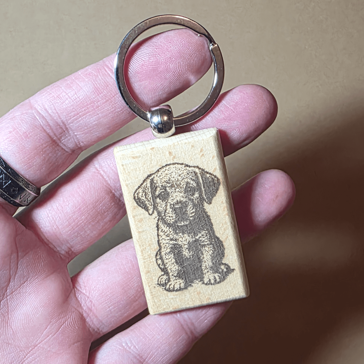 Close-up of wooden puppy keychain on neutral background