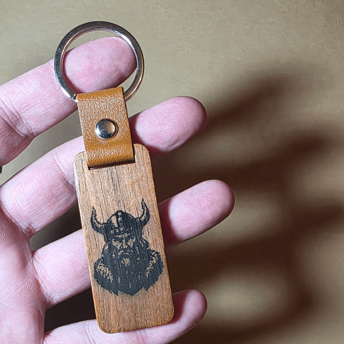 Close-up of engraved Viking warrior on dark walnut wooden keyring