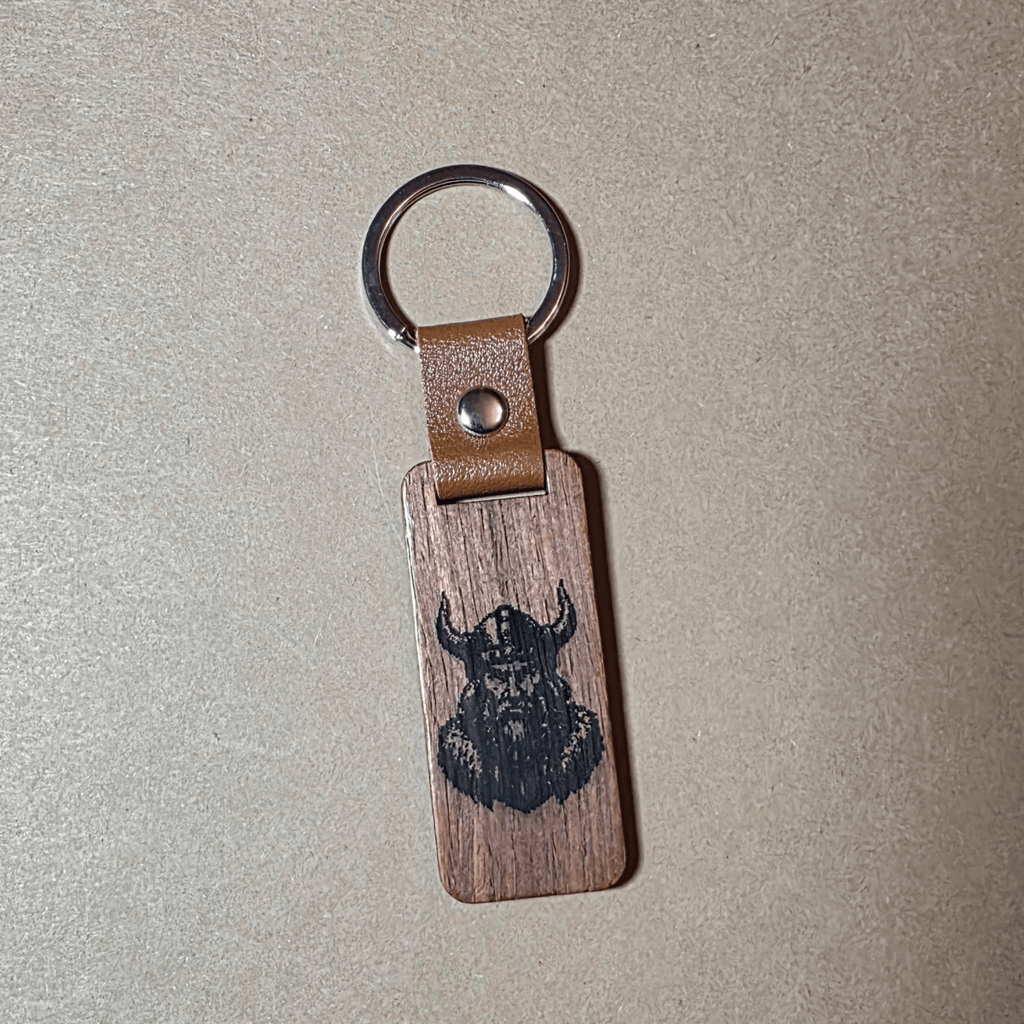 Viking wooden keychain with runes and leather strap lying on a neutral background