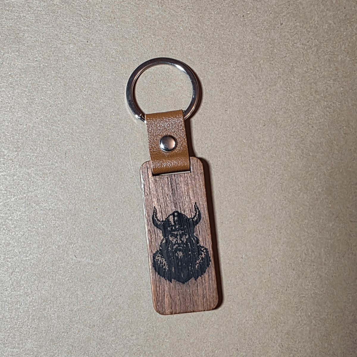 Viking wooden keychain with runes and leather strap lying on a neutral background